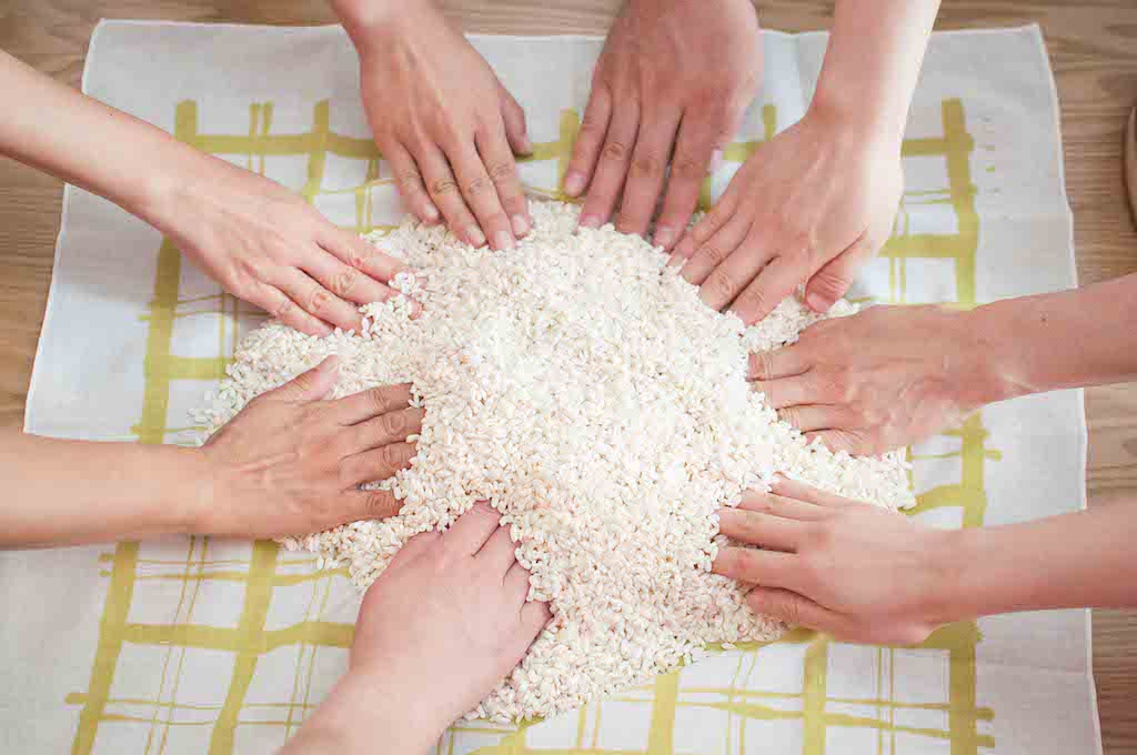 Eight hands touching rice together