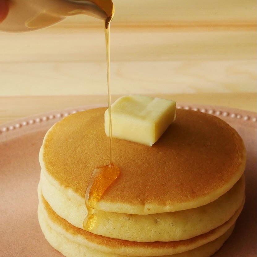 Pouring mirin syrup over double decker pancakes topped with square butter