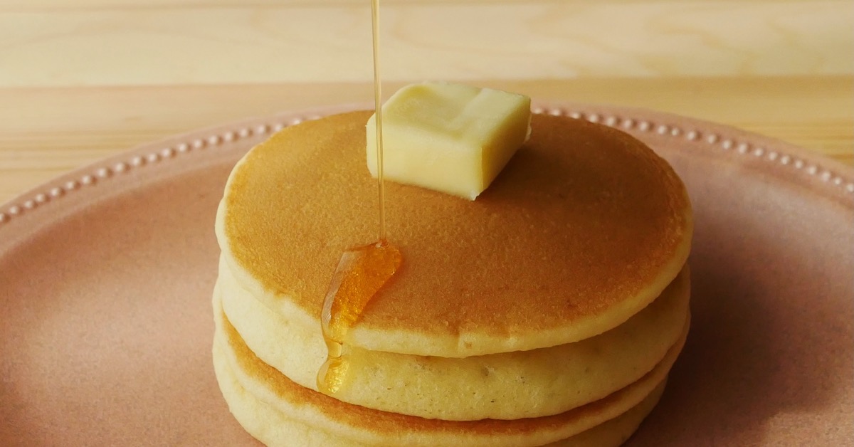 Pouring mirin syrup over double decker pancakes topped with square butter
