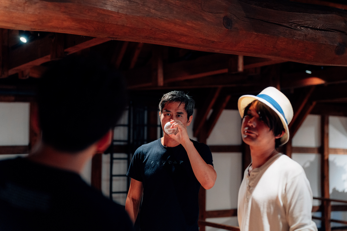 Takashi tasting liquid in a cup with Hiraku and the man in the brewary