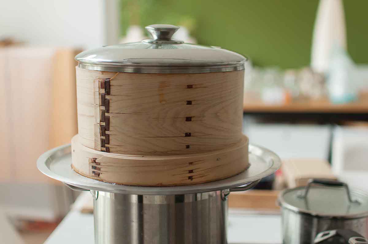 Rice being steamed in the bamboo container on the top of the stove