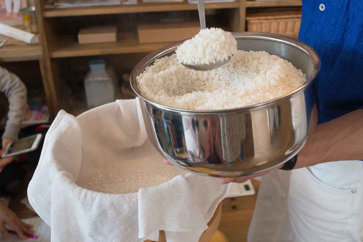Scooping washed rice in the silver bowl with the ladle 