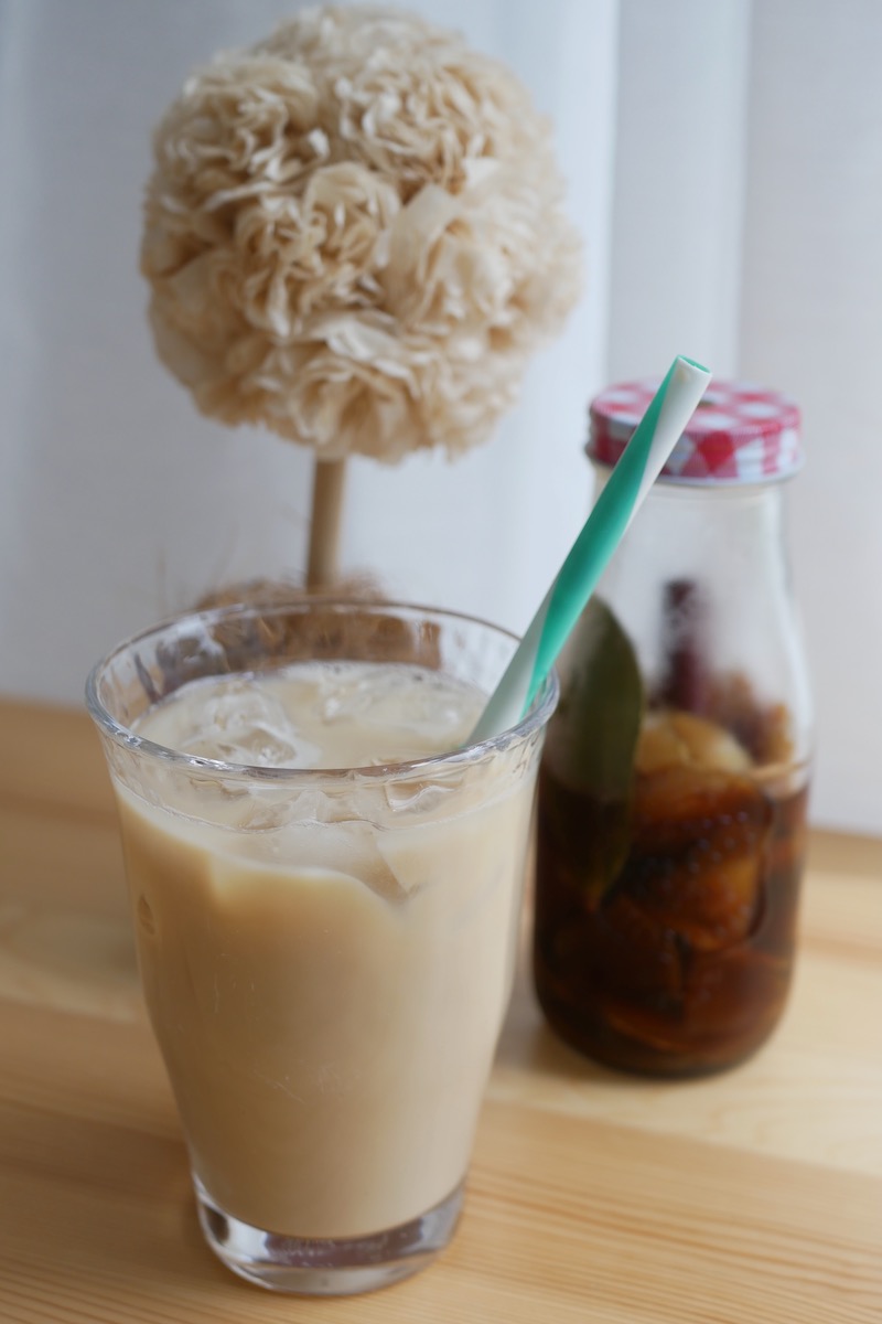 A glass of iced chai tea with a glass jar of apple and ginger mirin cordial