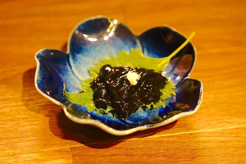 Black squid with grated ginger on shiso leave on a blue plate