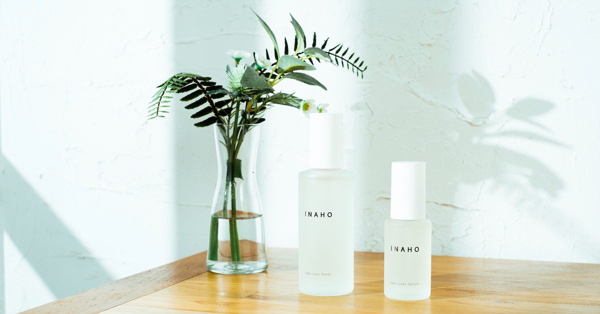 Two bottles of INAHO skincare products with a plant in a glass bottle